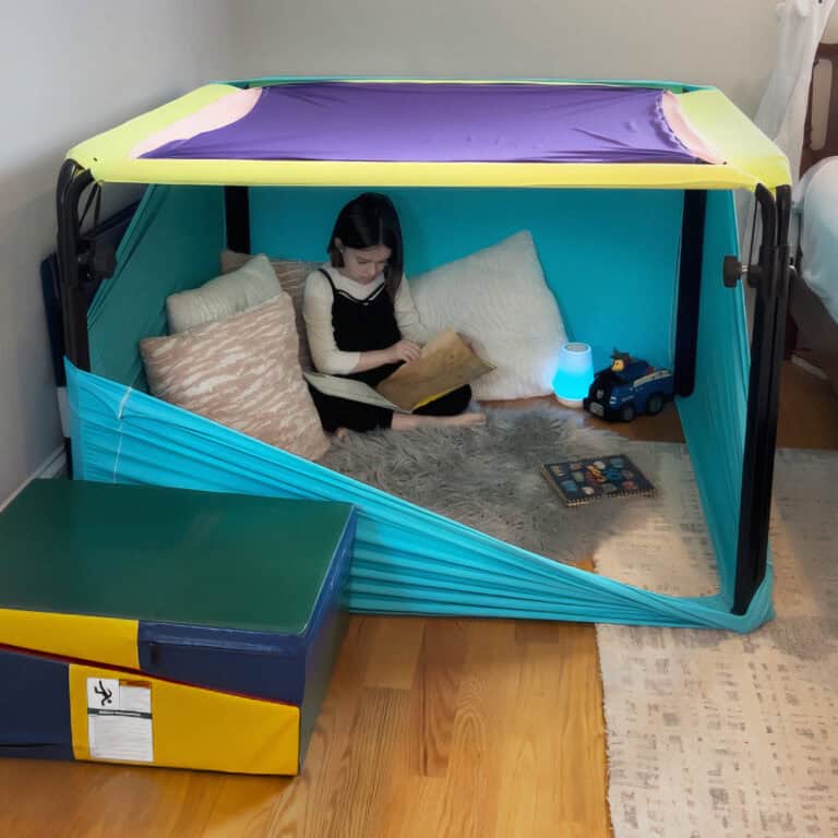 A photo of a child reading a book inside a Boundex Cuddle Box.