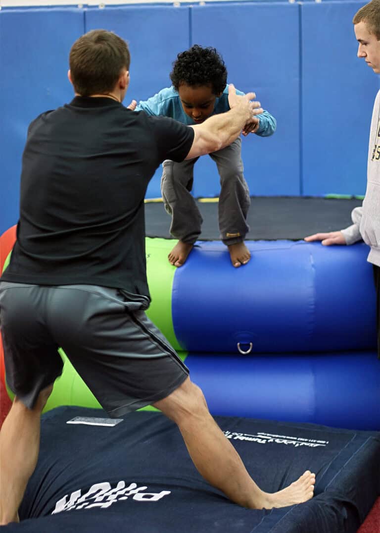 A photo of a client about to jump onto a Pit Pillow, guided by a pediatric OT.