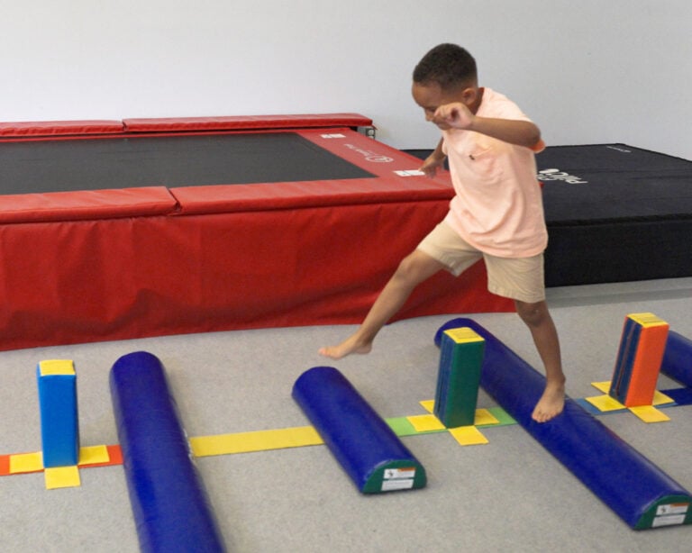 A photo of a boy jumping on a therapeutic obstacle course with Fun Sticks and Half Rounds.