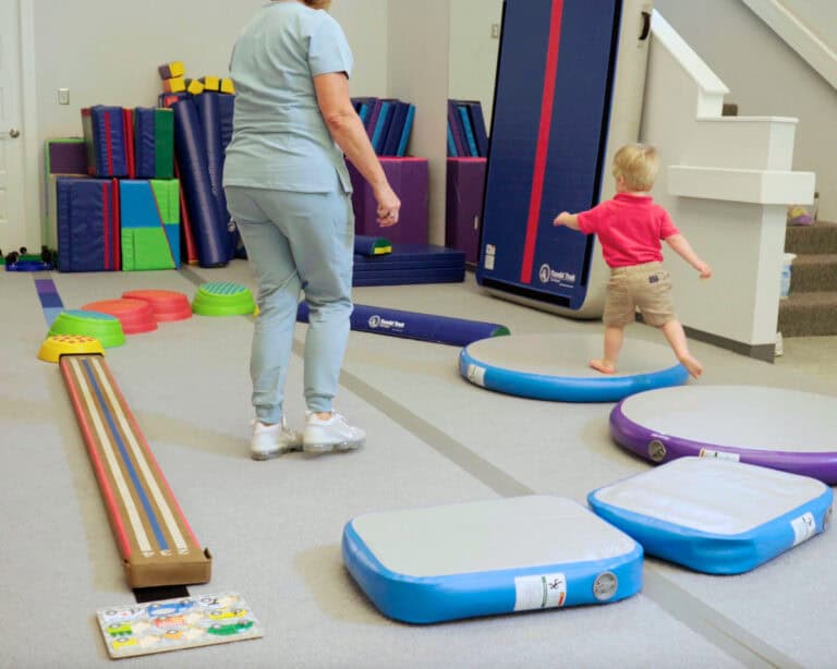 A photo of a boy at an OT clinic running across a progression of equipment including Hot Spots, Hot Blocks, a Laser Beam, and other products.