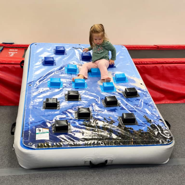 A photo of a girl in an OT clinic climbing down a Climbing Wall Overlay attached to an inclined Power Launch.
