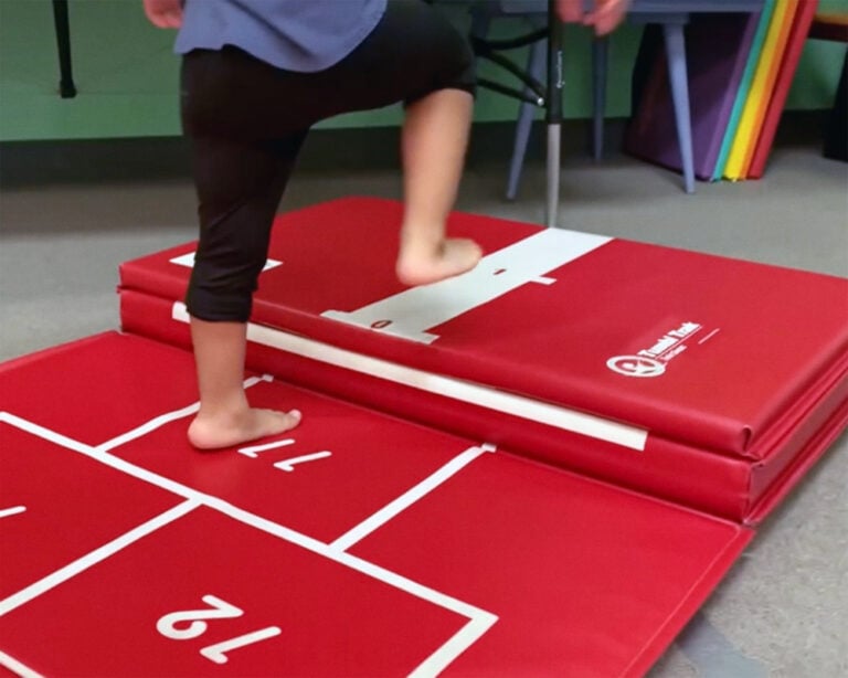 A photo of an occupational therapy client stepping onto the folded end of Hopscotch Mat.