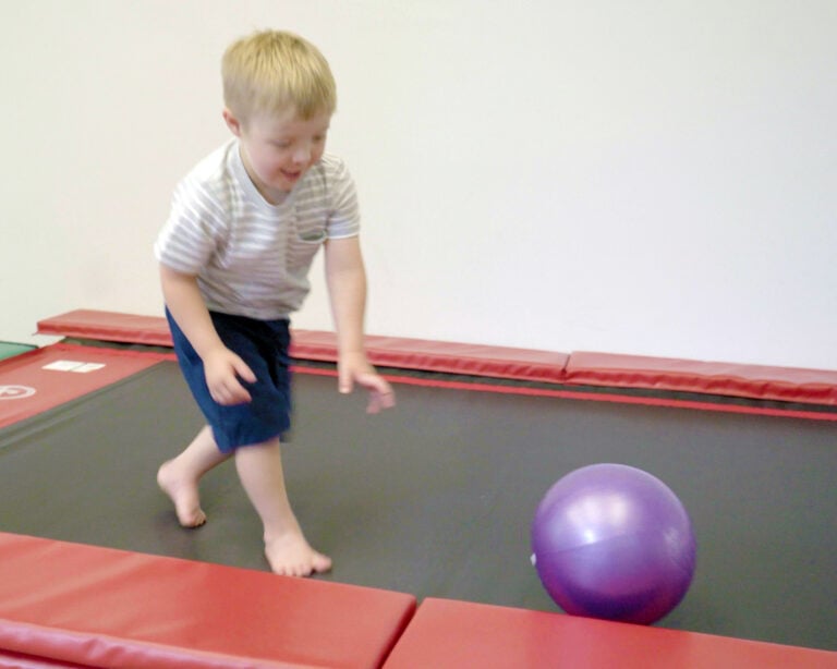 A photo of a boy chasing a ball on a Tumbl Trak.