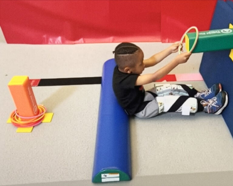 A photo of a boy doing a therapeutic exercise with rings and Fun Sticks.